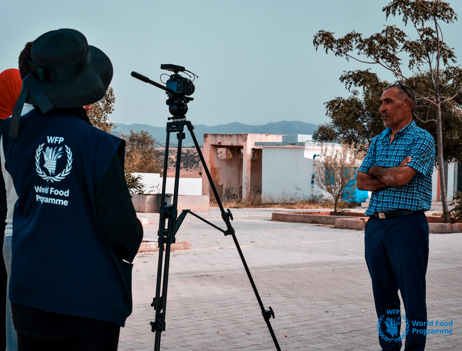 WFP personnel filming a field interview with a man.