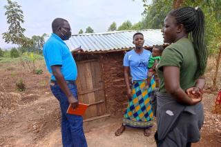 Dominic Aballa (holding notebook), WASH Officer, UNICEF Uganda, interacts with household member and community volunteer in Kikuube District, March 2022