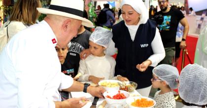 WFP official and a chef teaching children about healthy food choices.