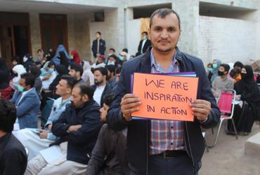 Ezat Ullah, national UN Volunteer Social Inclusion and Youth Empowerment Officer with UNDP Pakistan, holds a placard at an International Volunteer Day celebration in the refugee community on 5 December 2021. 