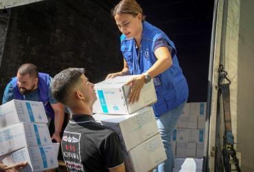 Workers off-loading relief supplies from a truck for distribution.